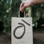 Kohi branded paper bag held outdoors featuring minimalist logo and tagline