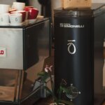 Close-up of espresso machine with Kohi logo and stacked branded coffee cups