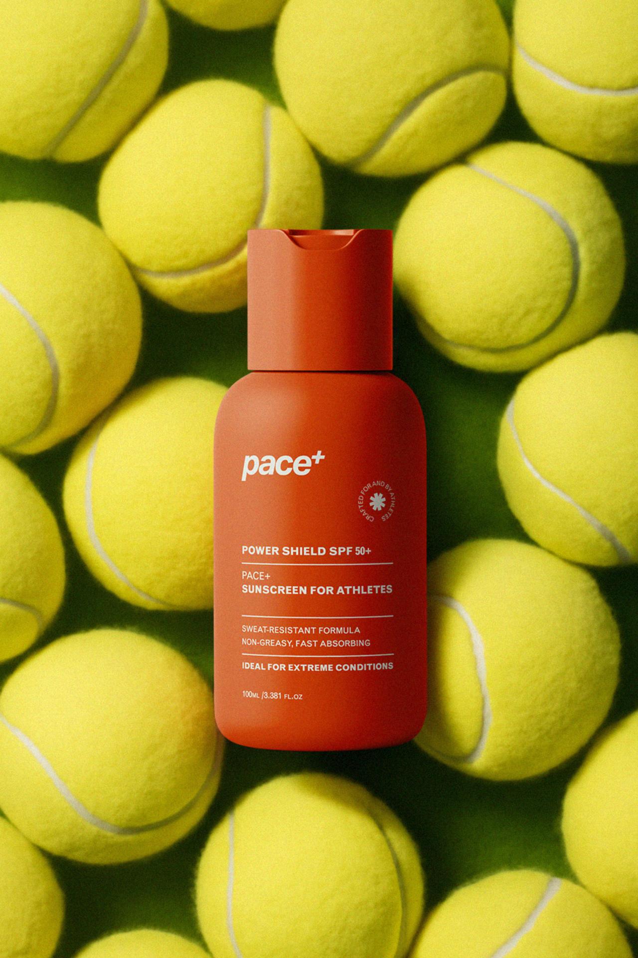 Pace+ SPF 50 sunscreen bottle placed among tennis balls emphasizing sport-specific skincare packaging